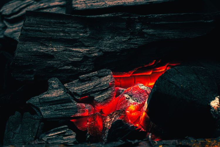 Campfire close up with dark burnt logs and a hot center of glowing embers